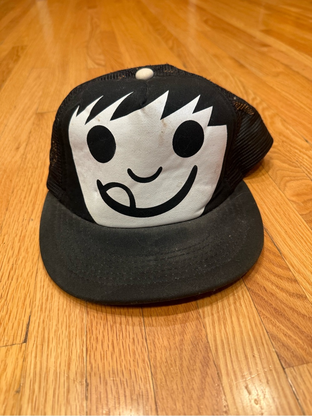 Sucka Character Black Trucker Hat with Playful White Face Graphic
